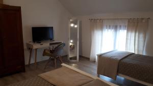Schlafzimmer mit einem Bett und einem Schreibtisch mit einem TV in der Unterkunft Apartman kod Kraljevih in Gola