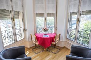 Un comedor con mesa y sillas y ventanas. en Hotel des Tourelles, en Ginebra