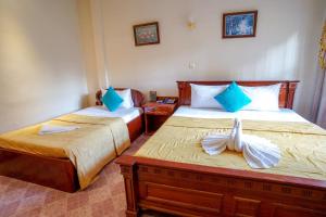 a bedroom with two beds with blue and white pillows at Royal Hotel in Battambang