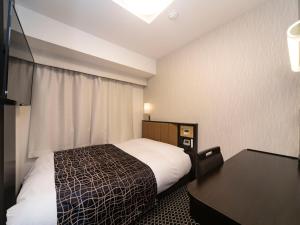 大阪市にあるアパホテル〈なんば駅東〉のベッドとテレビが備わる小さなホテルルームです。