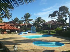 ein Pool mit zwei Rutschen in einem Garten mit Palmen in der Unterkunft Bangalô Menotti in Prado