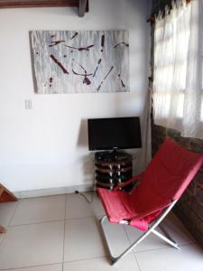 una silla roja en una habitación con TV en Bangalô Menotti, en Prado
