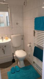 y baño con aseo, lavabo y alfombras azules. en Comfort en Hannover