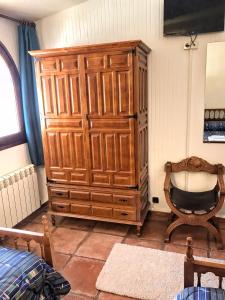 Un gran armario de madera en una habitación con una silla. en CASA TURÍSTICA Villa Carmen, CON AMPLIO JARDIN QUE INCLUYE BARBACOA, 2 PORCHES, PARKING PRIVADO Y PISCINA, en Arenzana de Abajo