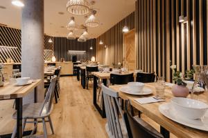 a restaurant with wooden tables and chairs and chandeliers at Ski&Sun Apartamenty in Świeradów-Zdrój