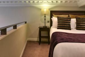 a bedroom with a bed and a lamp at Fraser Suites Queens Gate in London