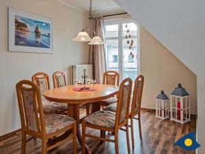 uma sala de jantar com uma mesa de madeira e cadeiras em Ferienwohnung Strandläufer 06 em Bansin