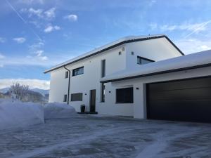 una casa blanca con un garaje en la nieve en Ferienwohnung Black White, en Raubling
