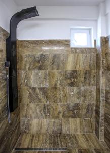 a shower in a bathroom with a stone wall at Lavender Villa in Mamaia Nord