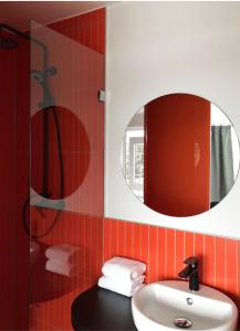ein Bad mit einem Waschbecken und einem Spiegel in der Unterkunft The Dot | 24/7 Checkin in München