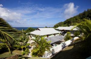 a house with a white fence and the ocean at Surfers Beach Self Catering Chalets in Takamaka