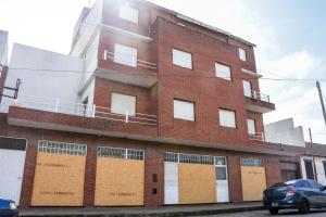 een bakstenen gebouw met bruine deuren en een auto voor de deur bij Hotel Puntarenas in Mar de Ajó