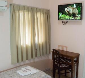 a room with a table and a television with a bear on the wall at Hotel Lobato in Paysandú