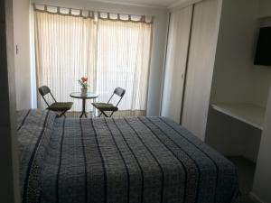 1 dormitorio con 1 cama, mesa y sillas en Hospedaje Amunátegui, en Iquique