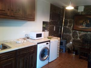 a kitchen with a washing machine and a microwave at Casa do Lagar in Resende