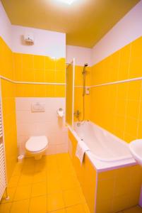 Baño amarillo con bañera, aseo y lavamanos en Hotel Smaragd, en Praga