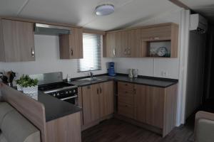 a kitchen with wooden cabinets and a stove top oven at Camping Parcvalrose Mobile Home No 79 in La Londe-les-Maures