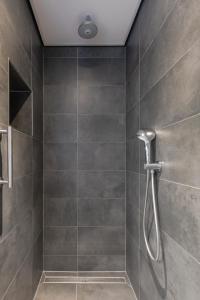 a bathroom with a shower with gray tiles at De Berkenhof Aparthotel in Nes