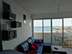 a living room with a couch and a view of the beach at Le Saint Roch - belle vue mer en plein centre ville in Palavas-les-Flots