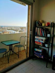 una mesa y una silla en una habitación con ventana en Le Saint Roch - belle vue mer en plein centre ville, en Palavas-les-Flots
