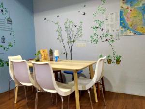 a wooden table with white chairs and a table with trees on the wall at Moon Eleven Hostel Near Klia & Klia2 in Sepang