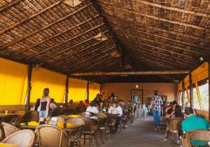 un grupo de personas sentadas en mesas en un restaurante en Lonier Ilha Inn Flats, en Abraão