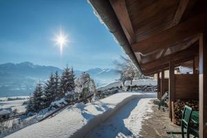 a snow covered porch of a house with the sun in the sky at Ferienwohnungen Vomperberg in Schwaz