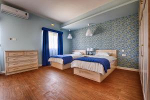 1 dormitorio con 2 camas, paredes azules y suelo de madera. en Aldo House en Għarb