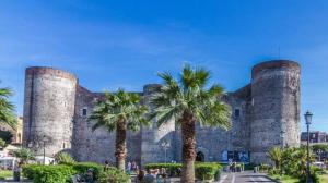 a large stone building with palm trees in front of it at Lina's House in Catania