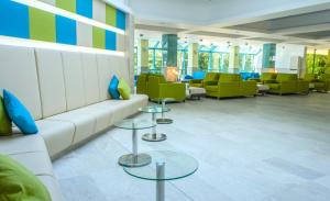 una sala de espera con un sofá blanco y sillas verdes en Hotel Boryana, en Albena
