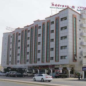 un grande edificio bianco con auto parcheggiate in un parcheggio di Address hotel Apartments العنوان للشقق الفندقية a Aş Şa‘arah