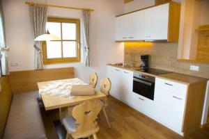 a kitchen with a wooden table and a table and chairs at Chalet Niederhaushof in Ultimo +87 photos