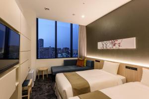 a hotel room with two beds and a window at hotel MONday Premium TOYOSU in Tokyo