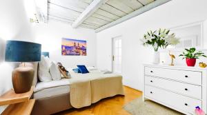 a white bedroom with a bed and a dresser at Royal Route Residence in Prague