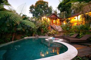 a swimming pool in a garden with a house at Umah Tis Sebatu in Tegalalang