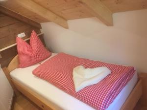 Bett mit roter und weißer Bettwäsche und einem herzförmigen Kissen in der Unterkunft Zirben Troadkasten in Liebenfels