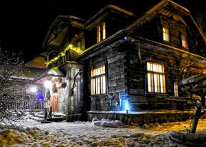 a wooden house with snow in front of it at night at Łosinek in Dolistowo