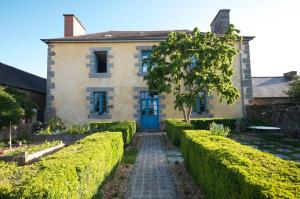 a house with a blue door and green hedges at Le Clos des Anges in Dingé