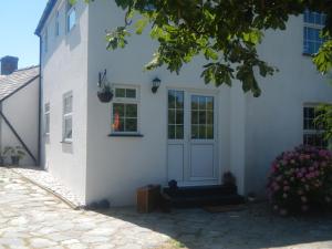 a white house with a door and a window at Boots Cottage in Bude