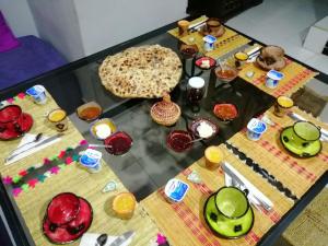 a glass table with plates and dishes on top of it at Maison d'h&ocirc;tes Dar El Nath in Ouarzazate