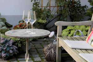 two wine glasses on a table next to a chair at Julius in der Pfalz in Hainfeld