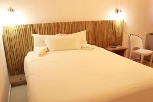 um quarto com uma cama grande com lençóis e travesseiros brancos em Pandeinge em Windhoek