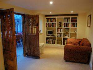 a living room with a chair and a book shelf at Gorse Farm House B&B in Sturminster Newton