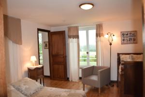ein Schlafzimmer mit einem Bett und einem Stuhl und einem Fenster in der Unterkunft Gîtes de la Croix du Bourg in Le Mesnil-Ozenne