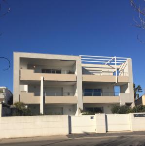 een wit appartementencomplex met een hek ervoor bij la scribote in Marseillan