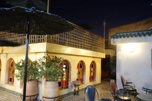 un edificio con mesas, sillas y sombrilla en Dar Al Madina Al Kadima, en Fez