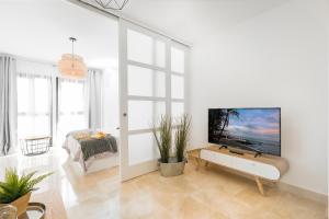 biały salon z telewizorem z płaskim ekranem na ścianie w obiekcie Apartamento Lujo Ancha del Carmen w Maladze