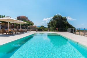 a pool with chairs and umbrellas next to the ocean at Dialiskari Villas in Marathopoli