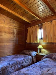 a bedroom with two beds in a log cabin at Cabañas Cortijo el Helao in Pozo Alcón
