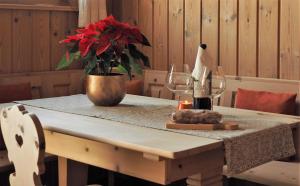 einen Tisch mit einer Vase aus roten Blumen und Weingläsern in der Unterkunft Chesa Sper l'Ovel Brail in Zernez